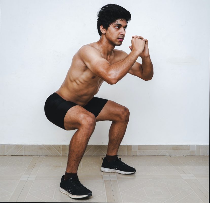 homme torse nu effectuant un squat